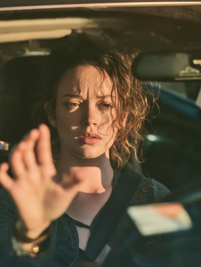 American driver examining a small windshield chip with a concerned expression from outside the glass